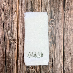 May include: White kitchen towel with a row of five embroidered green Christmas trees.
