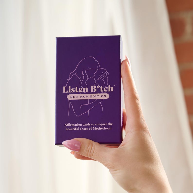 May include: Purple box of affirmation cards with the text "Listen B*tch" and "New Mom Edition". The box features a line drawing of a woman holding a baby.