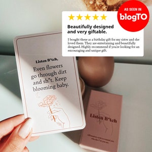 Puede incluir: Un juego de cartas de afirmaci&oacute;n con un fondo rosa y una ilustraci&oacute;n en blanco y negro de una mano sosteniendo una flor. El texto en la tarjeta dice "Listen B*tch, Even flowers go through dirt and sh*t. Keep blooming baby."