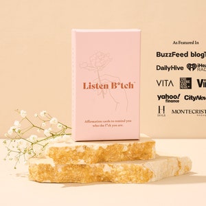Puede incluir: Una caja rosa con el texto "Listen B*tch" en la parte delantera. La caja est&aacute; sentada sobre dos rocas beige apiladas. El texto "As Featured In" est&aacute; en la parte superior de la caja, seguido de una lista de publicaciones y medios de comunicaci&oacute;n.