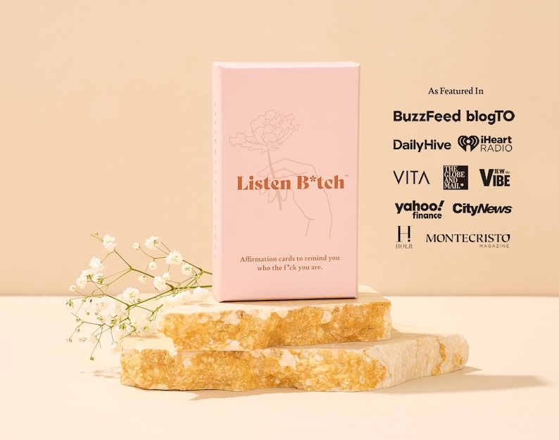 Puede incluir: Una caja rosa con el texto "Listen B*tch" en la parte delantera. La caja est&aacute; sentada sobre dos rocas beige apiladas. El texto "As Featured In" est&aacute; en la parte superior de la caja, seguido de una lista de publicaciones y medios de comunicaci&oacute;n.