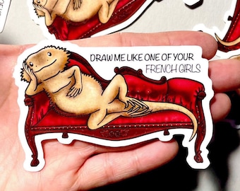 Puede incluir: Una pegatina con un dragón barbudo de dibujos animados descansando en una chaise longue de terciopelo rojo. El texto "Dibújame como una de tus chicas francesas" está escrito sobre el dragón.