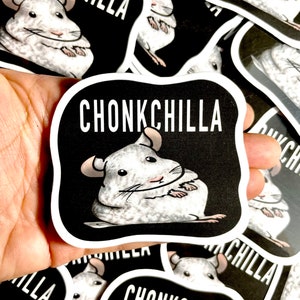 May include: A close-up of a sticker with a white chinchilla on a black background. The sticker says "Chonkchilla" in white text.