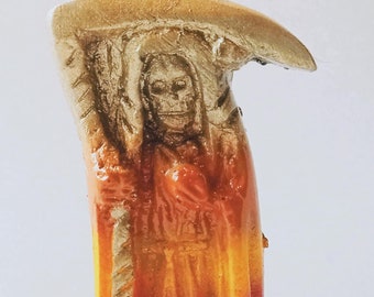 May include: A colorful figurine of the Grim Reaper holding a scythe. The figurine is painted in shades of red, orange, yellow, green, and blue. The base of the figurine is green and has a red rose.