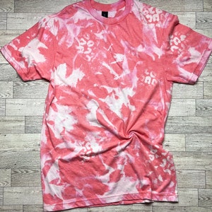 May include: A pink and white tie-dye t-shirt with a floral pattern.