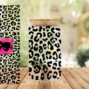 May include: A clear tumbler with a black and white leopard print design. The tumbler has a bamboo lid and a straw.
