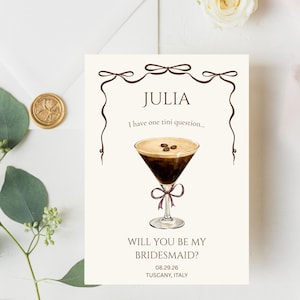 Könnte beinhalten: Eine rechteckige Karte mit cremefarbenem Hintergrund und einem braunen Linienrand mit Schleifen. Sie zeigt den Namen JULIA, den Text I have one tini question..., eine Martini-Glas-Illustration mit drei Kaffeebohnen und WILL YOU BE MY BRIDESMAID? 08.29.26 TUSCANY, ITALY.