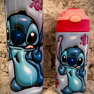 May include: Two stainless steel tumblers with a blue Stitch character from the Disney movie Lilo & Stitch. The tumblers have a light blue background with pink hibiscus flowers. The larger tumbler has a pink lid and the smaller tumbler has a pink lid with a pink straw.