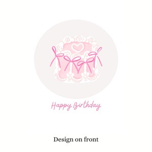 May include: A pink and white cake with a heart design and pink bows. The text "Happy Birthday" is written below the cake.
