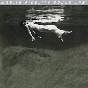 Puede incluir: Imagen en blanco y negro de una persona flotando bajo el agua, vestida con un vestido blanco. La superficie del agua es visible arriba, con el texto "MOBILE FIDELITY SOUND LAB" en la parte superior. La escena tiene una cualidad serena y onírica.