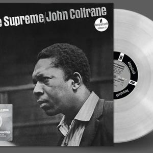 Może przedstawiać: Czarno-białe zdjęcie Johna Coltrane'a na okładce płyty winylowej zatytułowanej "A Love Supreme 50th Anniversary Edition". Płyta jest srebrna.