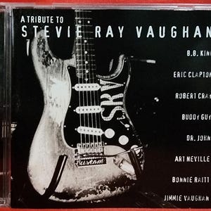 May include: A white ceramic mug with a black handle and the text "But First, Coffee" in a black, handwritten-style font. The mug is on a white surface.