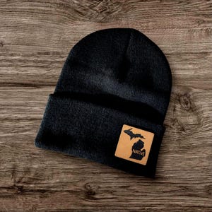 May include: Black beanie with a brown leather patch featuring the outline of Michigan and the word "NATIVE".
