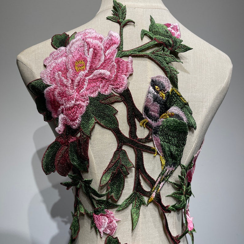 Pode incluir: Aplique bordado com uma flor de pe&ocirc;nia rosa, folhas verdes e dois p&aacute;ssaros empoleirados em um galho. O aplique &eacute; projetado para ser costurado em tecido.
