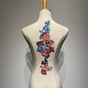 以下が含まれることがあります： 赤と青の花がついた花柄のアップリケ。服やクラフトにエレガントなアクセントを加えるのに最適です。