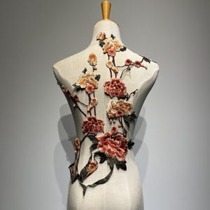 Puede incluir: Una aplicación floral con flores rosas y melocotón y hojas verdes sobre un fondo blanco.