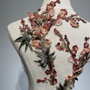 May include: A brown and green embroidered applique featuring a floral design with leaves and flowers. The applique is perfect for adding a touch of elegance to clothing, bags, or home decor projects.