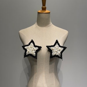 May include: Two black star-shaped pasties with white pearl embellishments.