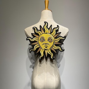Può includere: Toppa solare ricamata con un volto sorridente, colori giallo e marrone e contorno nero. Il sole ha raggi ondulati ed è attaccato a un manichino. Adatto per giacche, borse o altri articoli in tessuto.