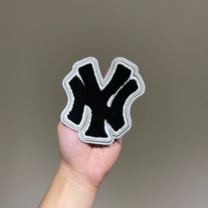 Op de afbeelding: Zwarte en witte geborduurde patch van het New York Yankees logo in graffiti-stijl.