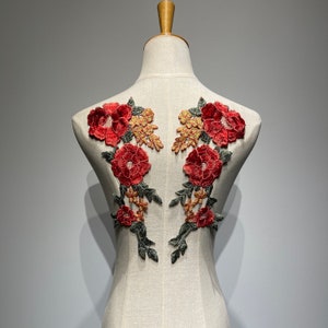 May include: Red and gold floral applique with a delicate design. The applique is perfect for adding a touch of elegance to any garment or craft project.