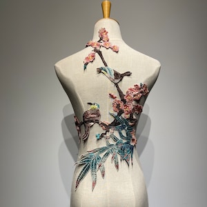Peut inclure: Une broderie florale délicate représentant des fleurs roses, des feuilles vertes et des oiseaux bleus. La broderie est idéale pour ajouter une touche d'élégance aux vêtements ou aux projets de décoration intérieure.