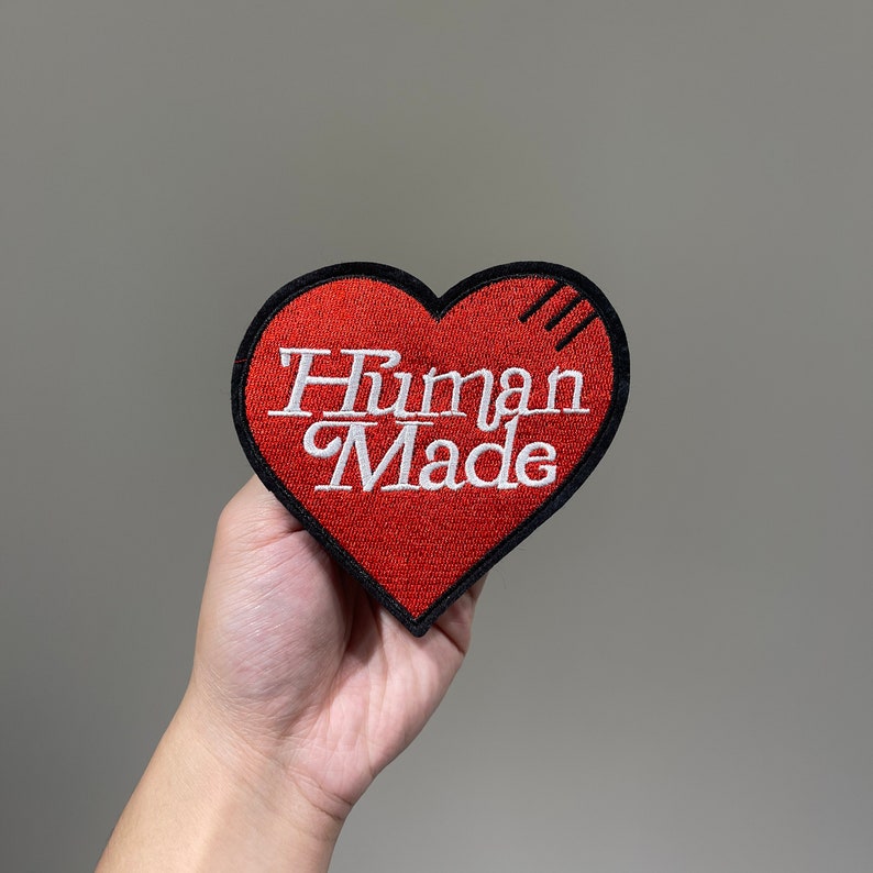 May include: Red heart-shaped patch with black stitching and the text "Human Made" in white embroidery.