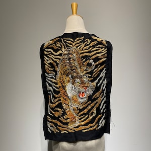 May include: Black fabric panel with an embroidered tiger design. The tiger is rendered in gold, brown, and white, with an open mouth and detailed fur. The background features gold and silver tiger stripes.