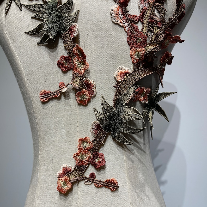 May include: A brown and green floral applique with a delicate design. The applique features small flowers and leaves, and is perfect for adding a touch of elegance to any project.