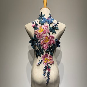 May include: A delicate floral applique featuring pink, yellow, and blue flowers with green leaves. The applique is perfect for adding a touch of elegance to clothing, accessories, or home decor.