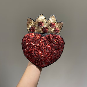 K&ouml;nnte beinhalten: Ein roter herzf&ouml;rmiger Patch mit goldenen Pailletten und einem Kronendesign. Der Patch besteht aus Stoff und Pailletten und ist perfekt, um jedem Projekt einen Hauch von Glanz zu verleihen.