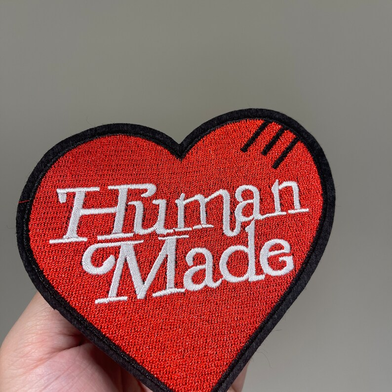 May include: Red heart-shaped patch with black stitching and the text "Human Made" in white embroidery.