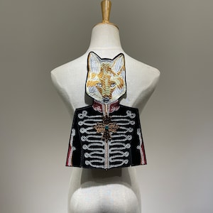 Könnte beinhalten: Aufbügelbarer Stickpatch mit einem Fuchs, der eine schwarze und goldene Militärjacke mit rotem Kragen und einem grünen Juwel-Akzent trägt.