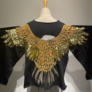 May include: Black long-sleeved shirt with a gold and silver sequined eagle design on the back.