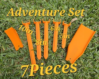 May include: A seven-piece orange plastic adventure set featuring various stakes and tools. The set includes items labeled with lengths of 10 inches, 8 inches, 6 inches, and 5 inches. The text Adventure Set and 7 Pieces is printed on the image.