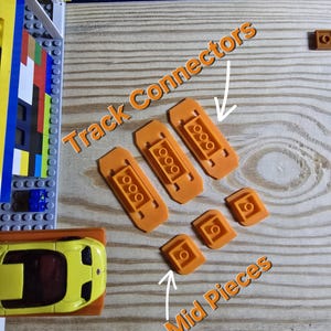 May include: Orange plastic track connectors and track pieces for a toy car racing set. The connectors have four holes and the pieces have one hole.