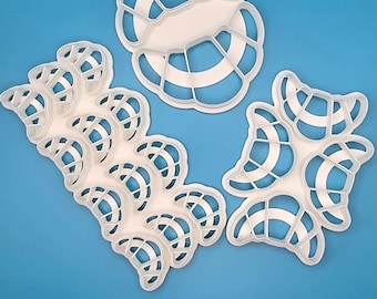 May include: Three white plastic cookie cutters shaped like crescent rolls. The cutters are on a blue background. Works on Dough and Soft Clay.
