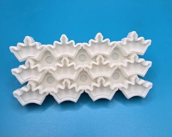 May include: A set of three white plastic cookie cutters shaped like crowns. The cutters are stacked on top of each other.