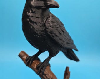 May include: A black raven figurine with detailed feather textures and a white eye, perched on a brown textured tree branch. The bird is mounted on a circular black base, showcasing a realistic pose with its head turned to the side.