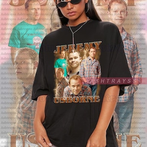 May include: Black unisex t-shirt featuring a collage of images of Jeremy Usborne, with the text "JEREMY USBORNE" in a vintage style. The model is wearing a 2XL shirt. A perfect gift for fans.