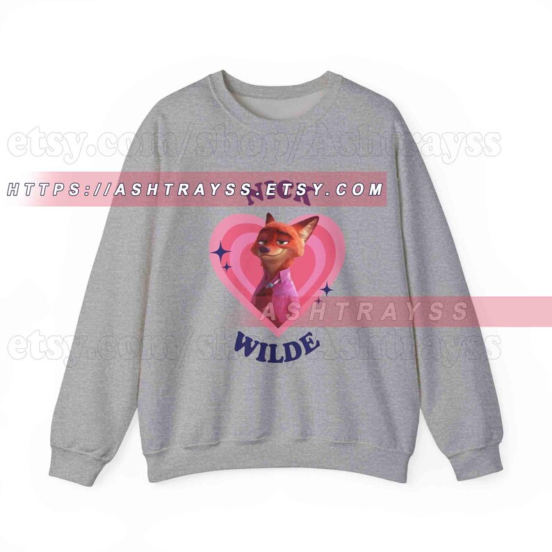 May include: A gray sweatshirt featuring a cartoon image of Nick Wilde from Zootopia inside a pink heart. The text "Nick Wilde" is above the image, and "Wilde" is below. The Etsy shop URL is visible.