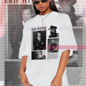 May include: White t-shirt with a black and white photo collage of Eric Winter. The collage includes four photos of Winter in different poses. The text "Eric Winter" is printed above the collage. The t-shirt is oversized and the model is wearing a size 2XL.