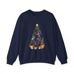 May include: A navy blue sweatshirt with a Christmas tree design composed of dogs. The tree is adorned with a gold star and surrounded by wrapped presents. The dogs are in shades of black, brown, and grey.