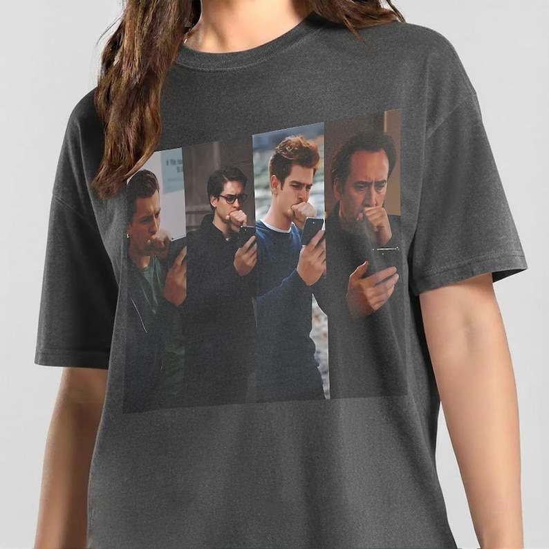May include: A charcoal gray short-sleeve t-shirt featuring a rectangular graphic print of four different men, each holding a smartphone to their ear or looking at a screen, with each individual captured in a separate vertical panel on the front.