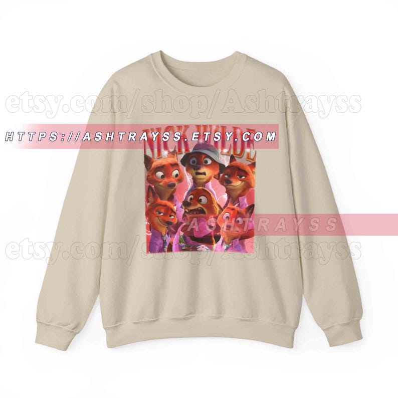 Puede incluir: Sudadera beige con un gr&aacute;fico de varios zorros de dibujos animados y el texto "NICK WILD" en rojo. Los zorros est&aacute;n en varias poses y visten camisas moradas. La sudadera tiene mangas largas y cuello redondo.