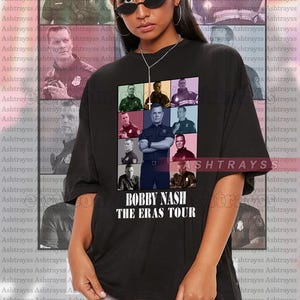 Può includere: Maglietta nera con un collage di foto di un uomo in diversi abiti. Il testo "BOBBY NASH THE ERAS TOUR" è stampato sulla maglietta.