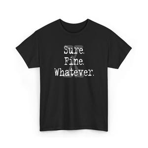 Può includere: T-shirt nera con la scritta bianca "Sure. Fine. Whatever." in un carattere di macchina da scrivere. La maglietta è a girocollo, adatta per l'abbigliamento casual.