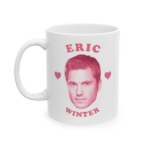 May include: White ceramic mug with a pink image of Eric Winter, the text "ERIC WINTER" and two pink hearts.