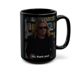 Puede incluir: Una taza de cerámica negra con una imagen impresa de una persona con cabello largo y rubio que usa gafas de sol oscuras. La persona viste una chaqueta negra frente a una estantería. El texto "No, thank you!" está impreso en color blanco.