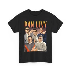 May include: Black t-shirt featuring a collage of Dan Levy in various poses, with the name "DAN LEVY" in a retro font across the top. The image has a vintage, faded aesthetic.